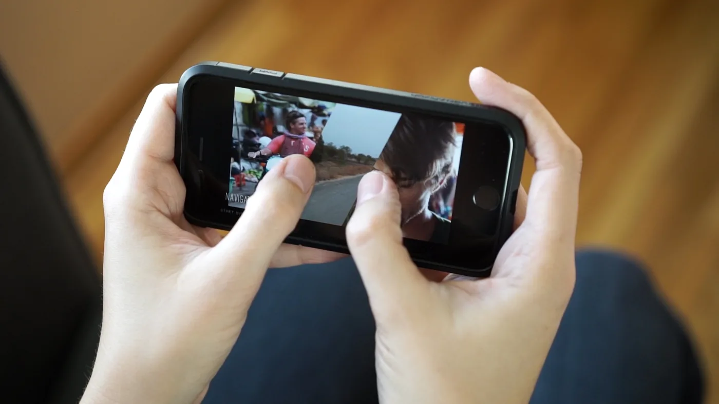 Hands holding an iPhone playing Invisible World’s split-screen film